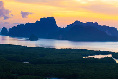 Scenic view of sea and silhouette mountains against sky during sunset