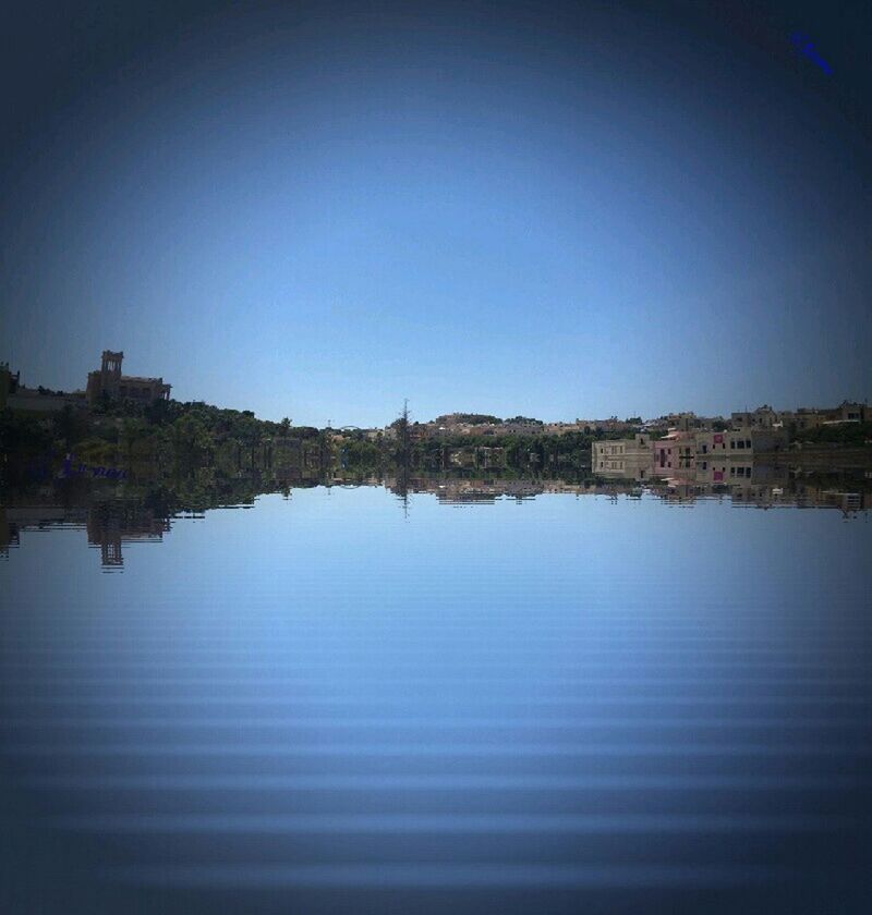 clear sky, building exterior, water, copy space, architecture, waterfront, built structure, reflection, blue, river, tranquility, lake, tranquil scene, mid distance, city, sea, scenics, nature, outdoors, vignette