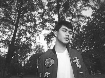 Portrait of young man standing against trees