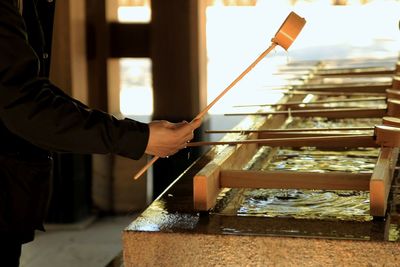 Side view of man holding ladle while standing by pond