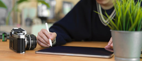 Midsection of woman photographing with smart phone on table