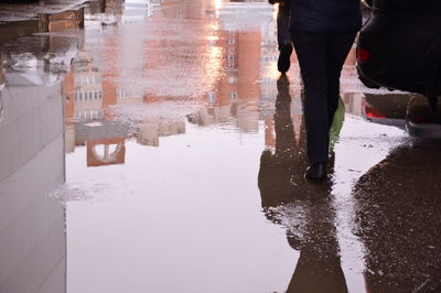 Low section of man walking on wet street