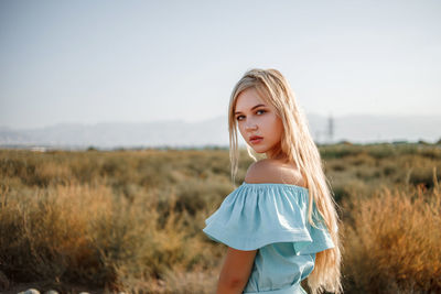 Portrait of teenage girl wearing dress standing on land against sky