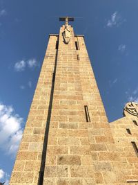 Low angle view of cross on building against sky