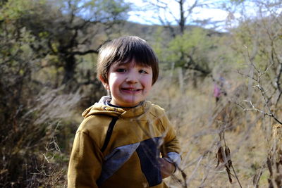 Portrait of smiling boy standing in forest