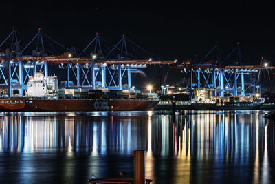 Illuminated harbor by river at night