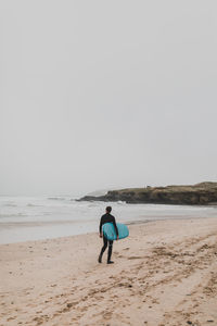 Rear view of man on beach against clear sky