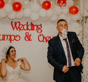 Portrait of young couple standing against wall
