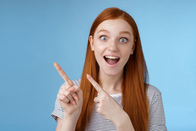 Surprised woman pointing against blue background