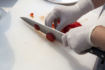 Cropped image of chef cutting tomato on board