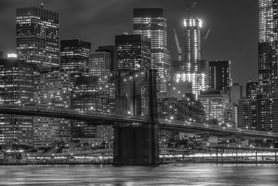 Brooklyn bridge over east river against illuminated buildings