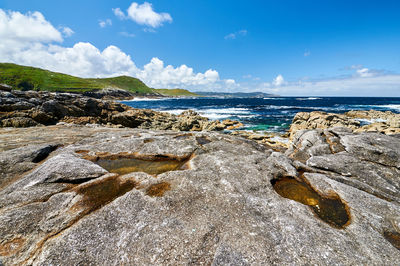 Scenic view of rocks on beach against sky