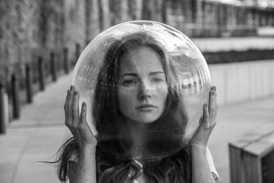 Young woman looking away while wearing glass helmet in head on sidewalk