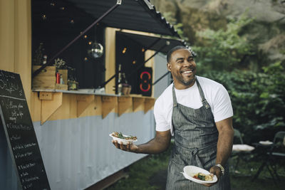 Smiling male seller with food looking away in park