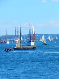 Sailboats sailing on sea against blue sky