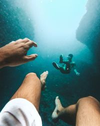 Low section of man swimming with male friend in sea