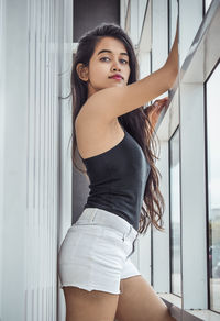 Portrait of beautiful young woman standing against wall