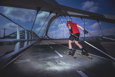 Athlete ski rolling on bridge at dusk