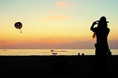 Silhouette people on beach against sky during sunset