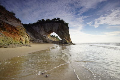 Rock formations on beach against sky