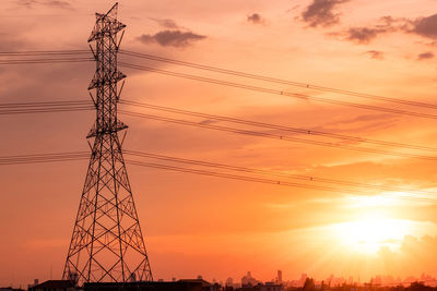 High voltage electric pylon and transmission lines with sunset sky and cityscape. electricity.