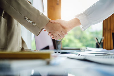 Midsection of business people shaking hands in office