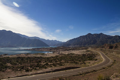 Scenic view of road by mountains against sky