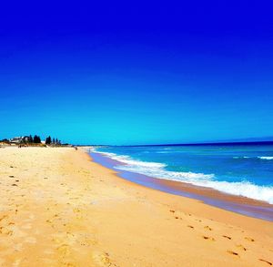 Scenic view of beach against clear blue sky