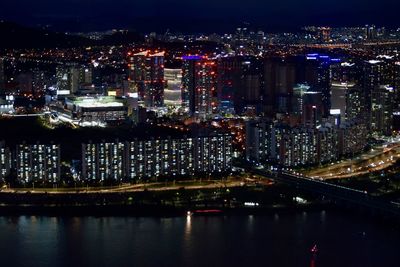 High angle view of illuminated city by river at night