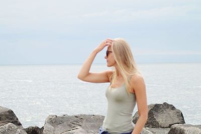 Young woman looking at sea against sky