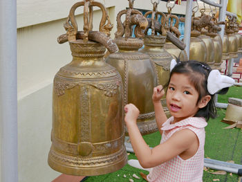 Close-up portrait of girl ringing bell at temple