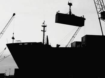 Low angle view of silhouette cranes against sky