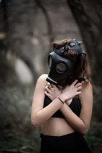Woman wearing gas mask while covering chest