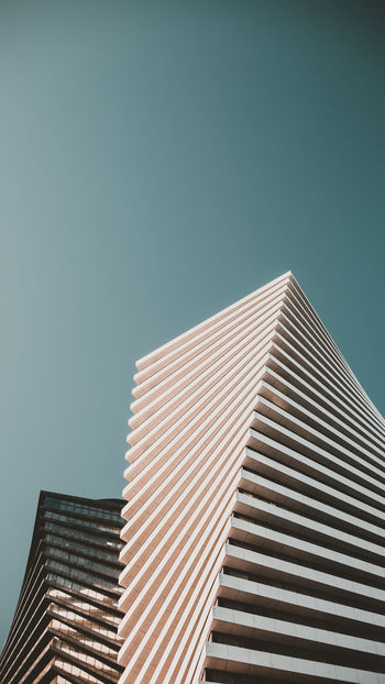 LOW ANGLE VIEW OF MODERN BUILDING AGAINST CLEAR BLUE SKY