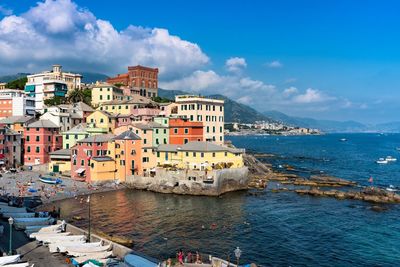 Buildings by sea against sky