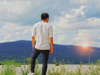 Rear view of man standing on field against sky