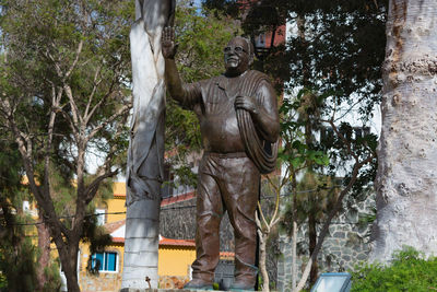 Low angle view of statue against trees and building