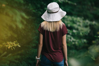 Rear view of woman standing against trees