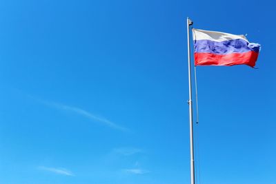 Low angle view of flag against blue sky