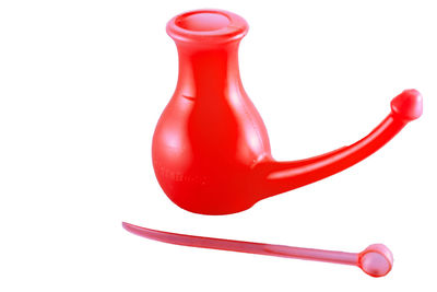 Close-up of red neti pot against white background