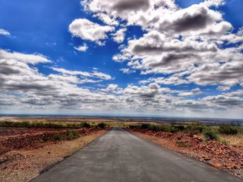 Empty road amidst land against sky
