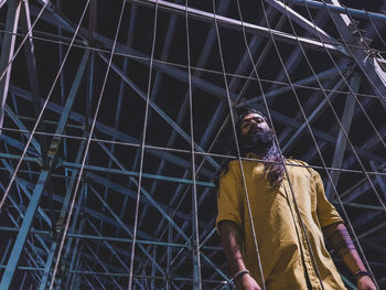 Low angle view of man amidst metal structure