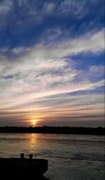 Scenic view of sea against cloudy sky at sunset