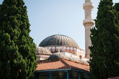 Low angle view of historical mosque building against sky between two trees