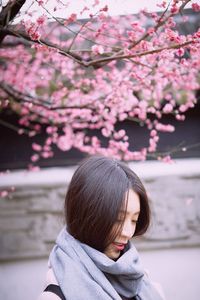 Close-up of young woman against pink flowers