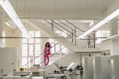 Businesswoman with hand in hair standing on steps at industry