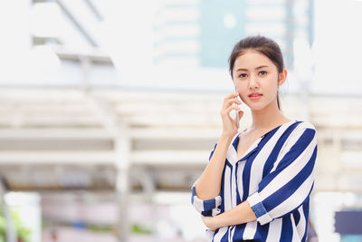 Portrait of young woman standing on mobile phone