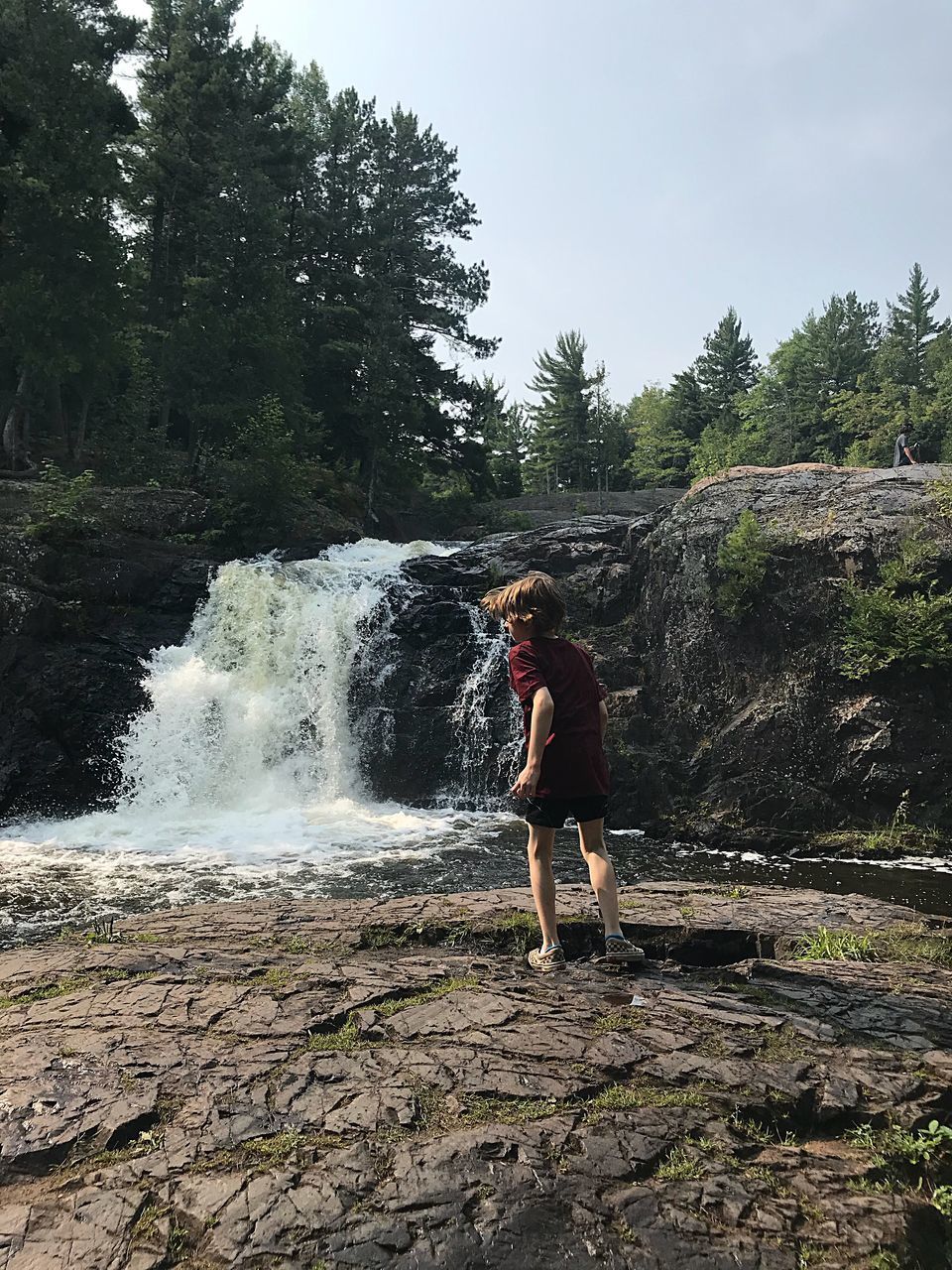 MAN STANDING AGAINST WATERFALL