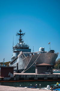 Ship moored at harbor against clear blue sky