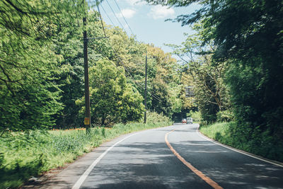 Empty road amidst trees against sky